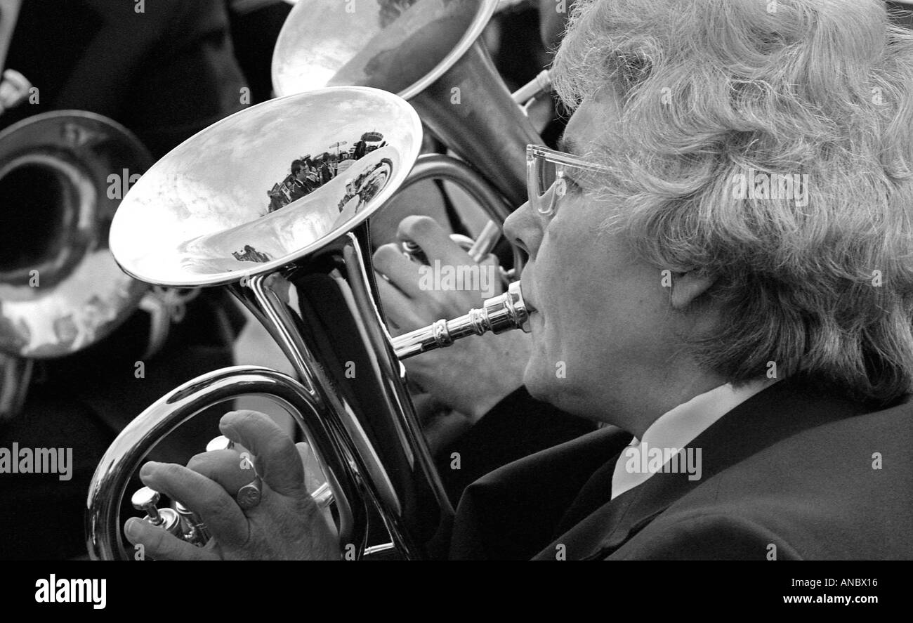 Close up di lady suonare la tromba in una banda di ottoni con la riflessione degli altri membri della band in metallo lucido Foto Stock