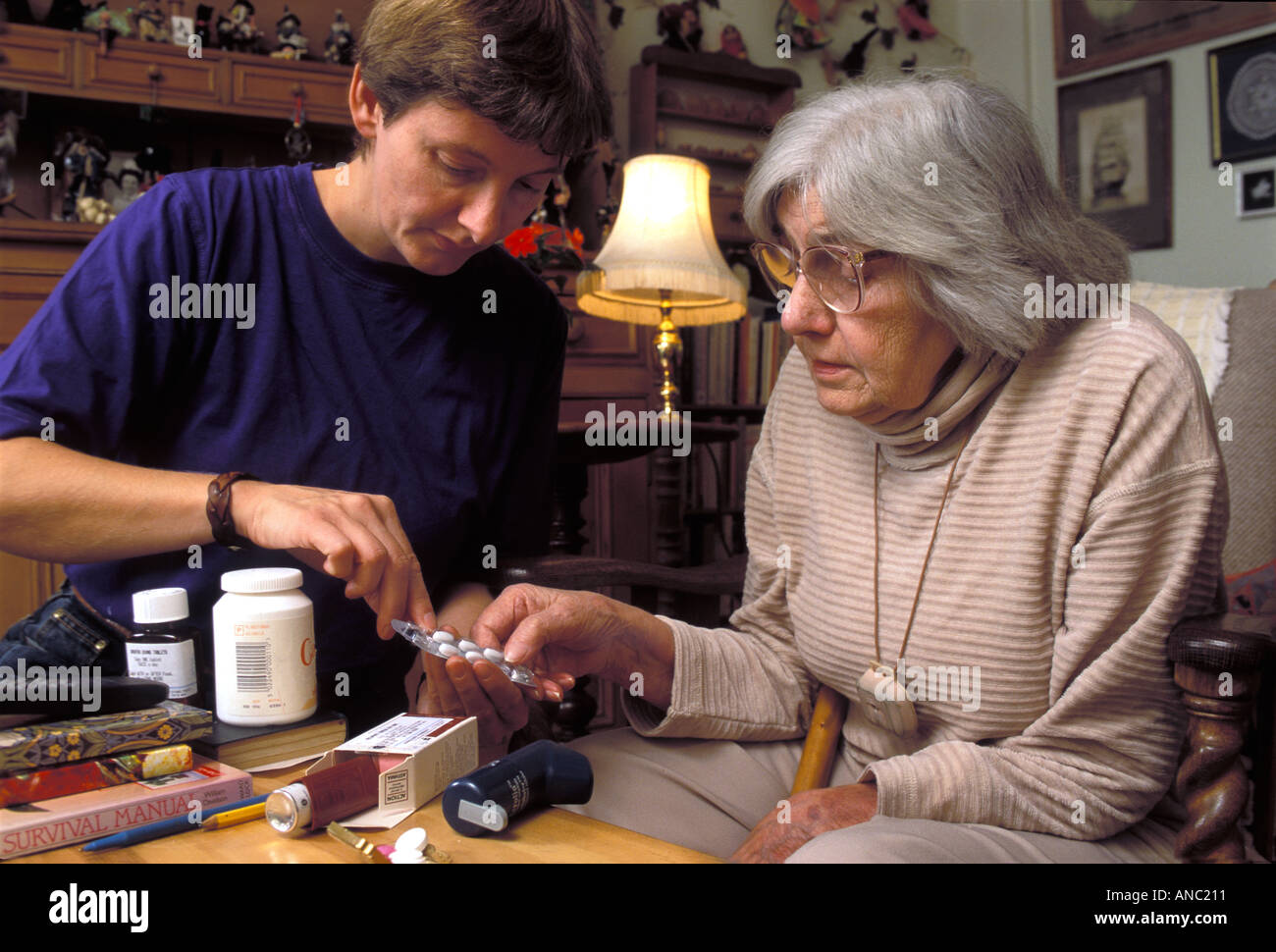 Donna anziana nella propria casa di essere aiutato con le sue pillole e medicinali per un caregiver REGNO UNITO Foto Stock