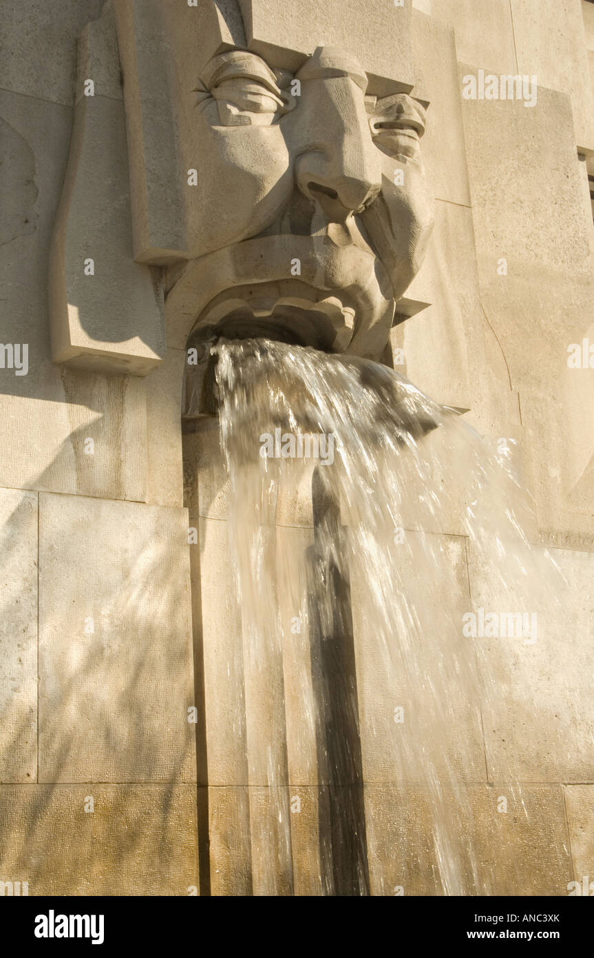 Acqua che sgorga e la colata dalla bocca di pietra figura nella fontana della piazza insieme nella parete della stazione centrale di Milano Foto Stock