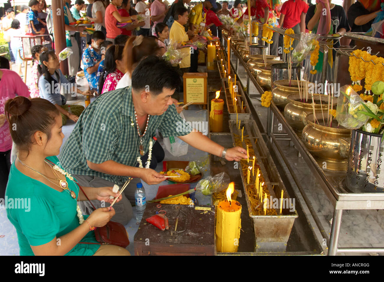 Buddisti accendendo candele, pilastro della città santuario, Bangkok, Thailandia Foto Stock