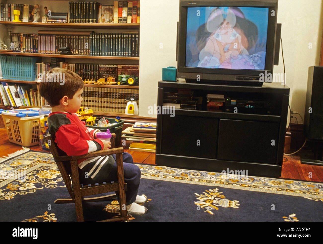 Bambino di due anni a guardare la televisione tv cartoons sippy Cup e la sedia a dondolo giocattoli Foto Stock