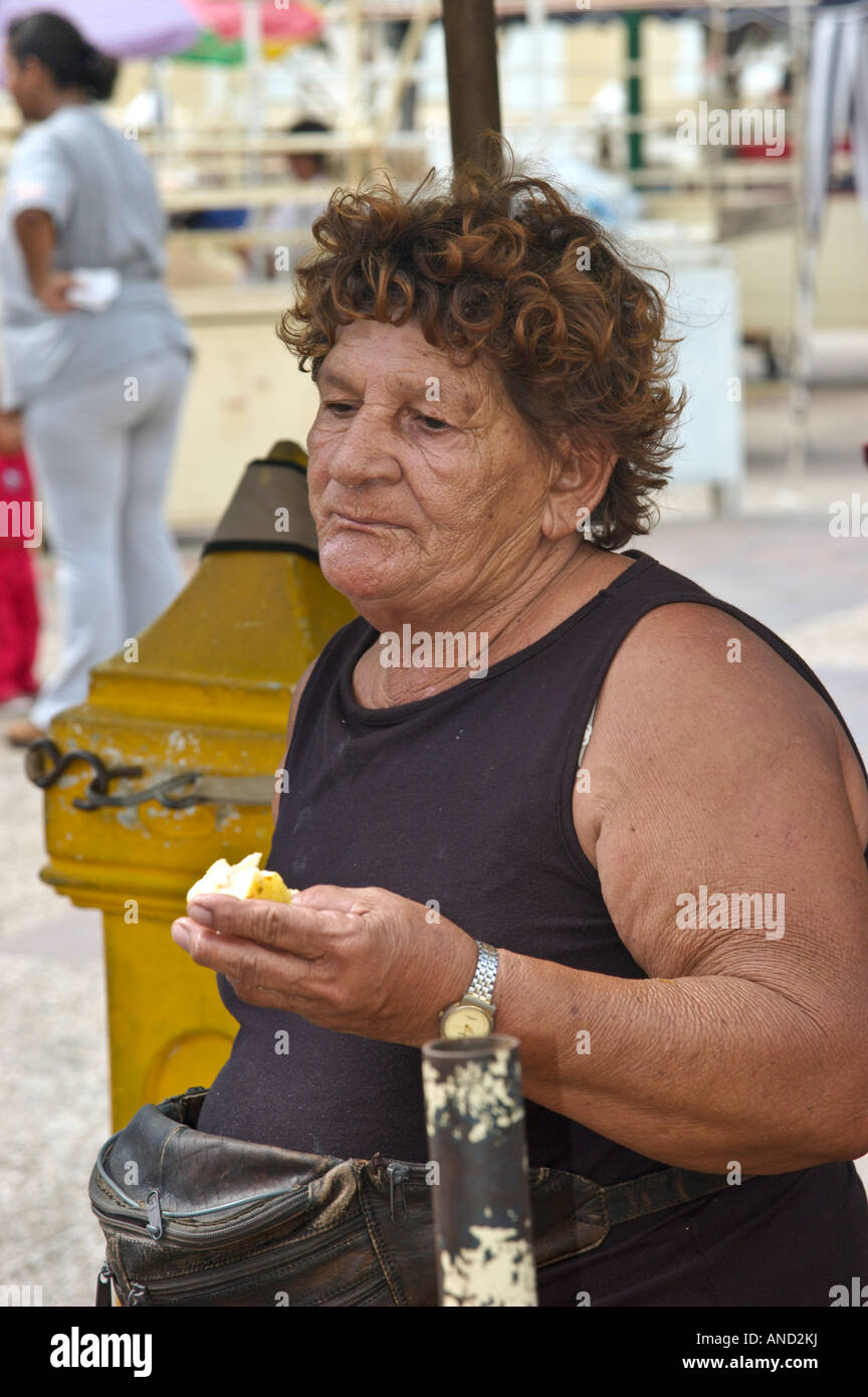 Anziani stallholder prende tempo per un piccolo spuntino, Isla Margarita, Venezuela Foto Stock