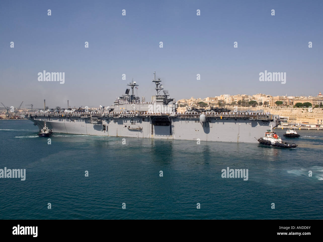 L'assalto anfibio nave USS Kearsarge è assistita da rimorchiatori come ella cuccette in Malta il Grand Harbour Foto Stock