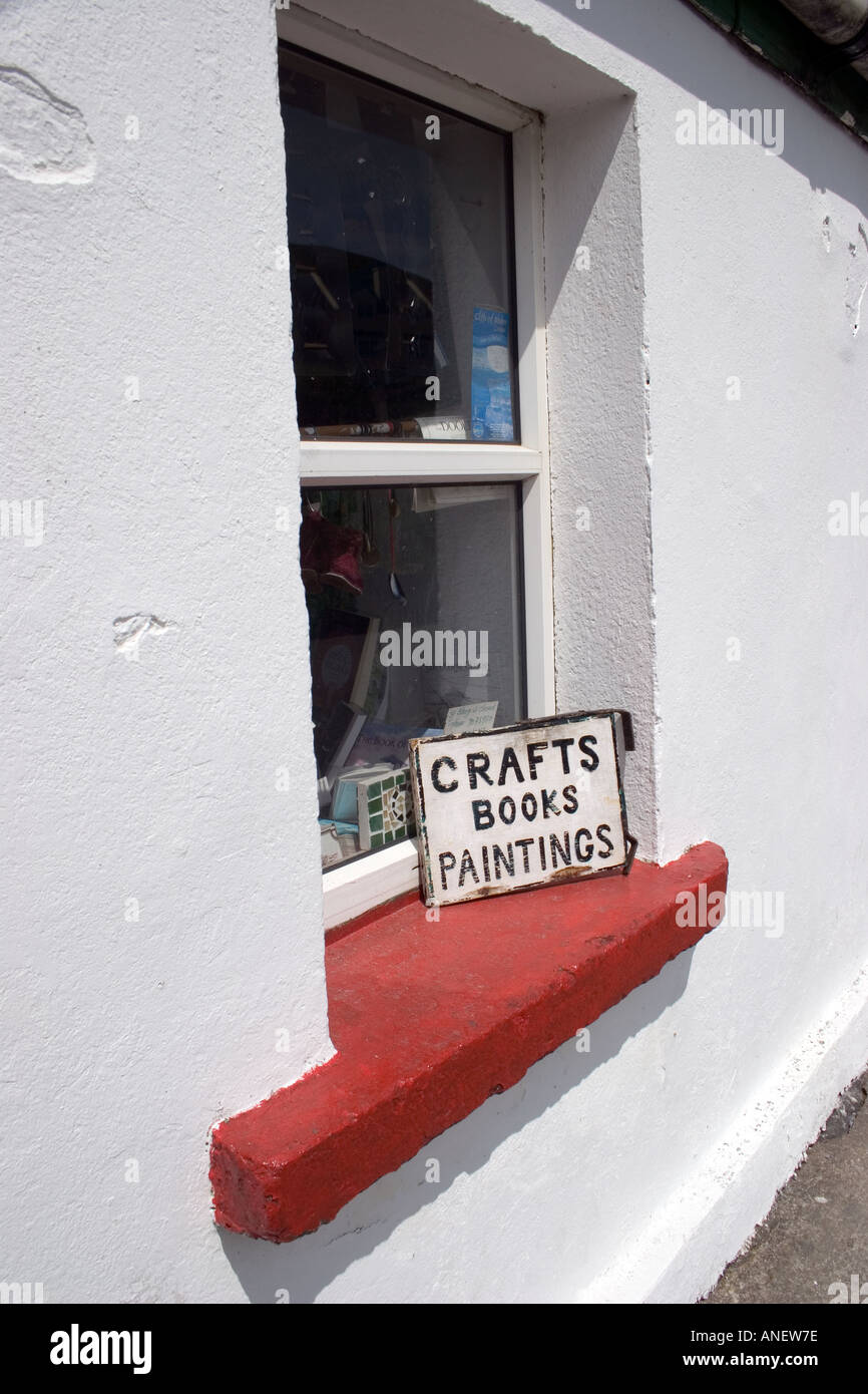 Finestra dipinte di bianco con la finestra rossa battuta e segno di artigianato. Doolin, County Clare, Irlanda. Foto Stock