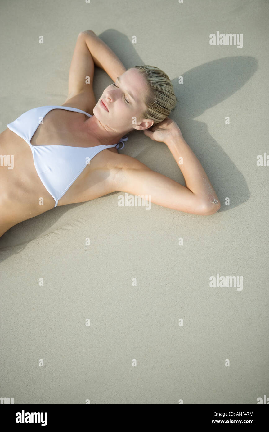 Giovane donna in bikini giacente sulla spiaggia, vita fino Foto Stock