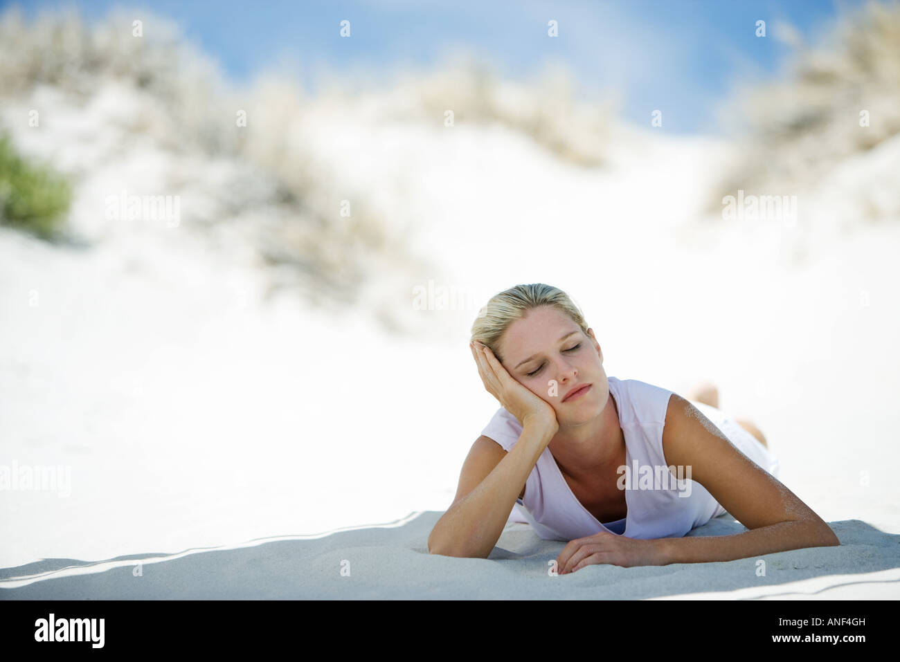 Donna sdraiata sulla spiaggia a occhi chiusi Foto Stock