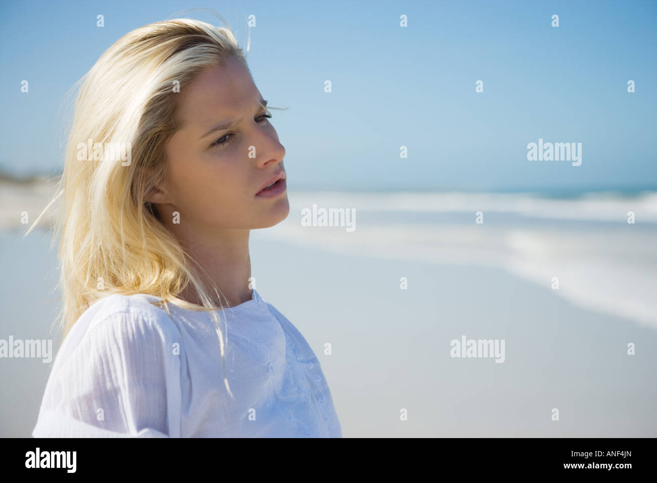Giovane donna sulla spiaggia, guardando lontano, la testa e le spalle Foto Stock