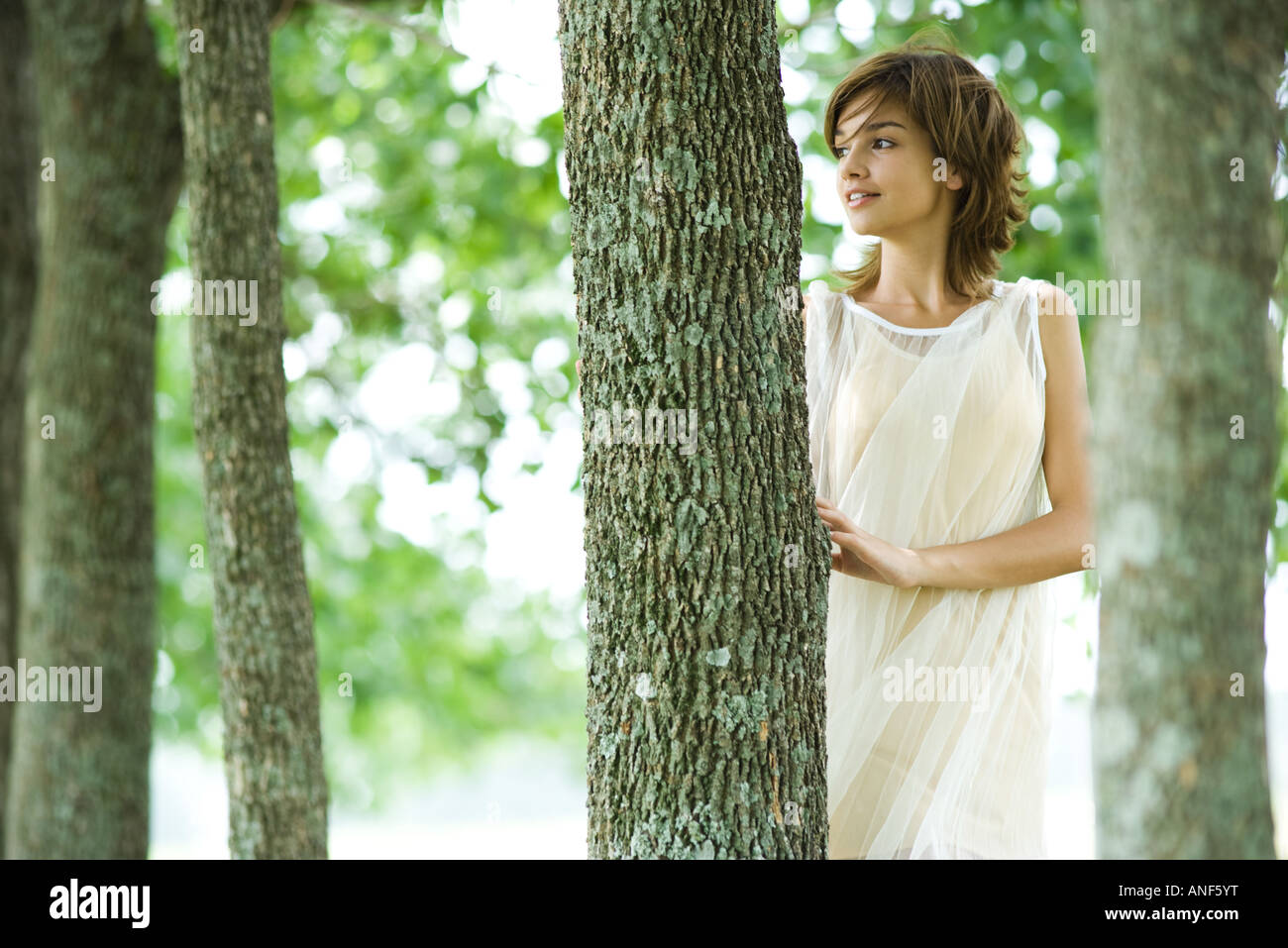 Giovane donna che indossa abiti in piedi nei boschi, guardando lontano Foto Stock