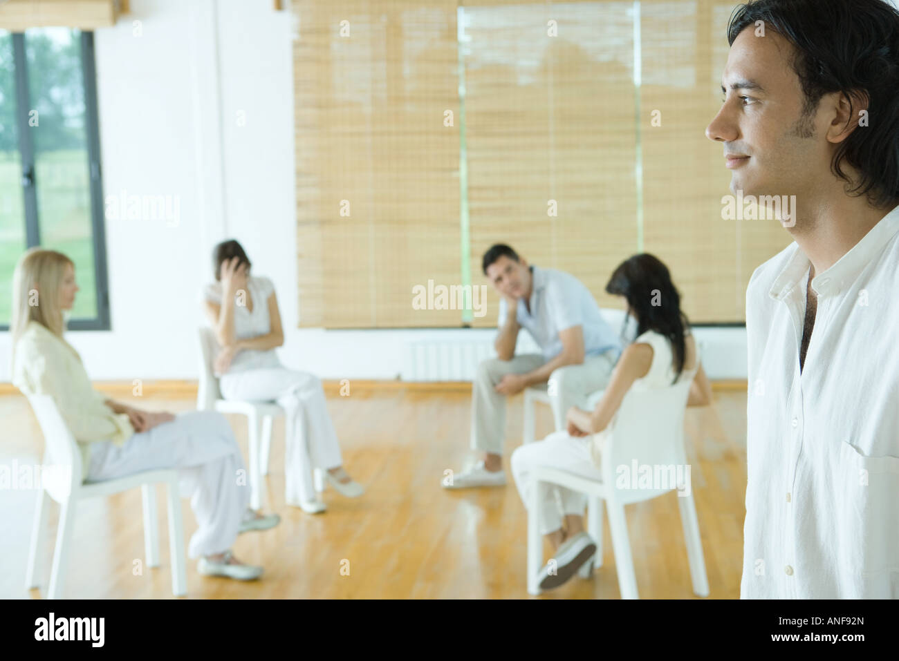 La terapia di gruppo sessione, l'uomo in piedi in primo piano, sorridente Foto Stock
