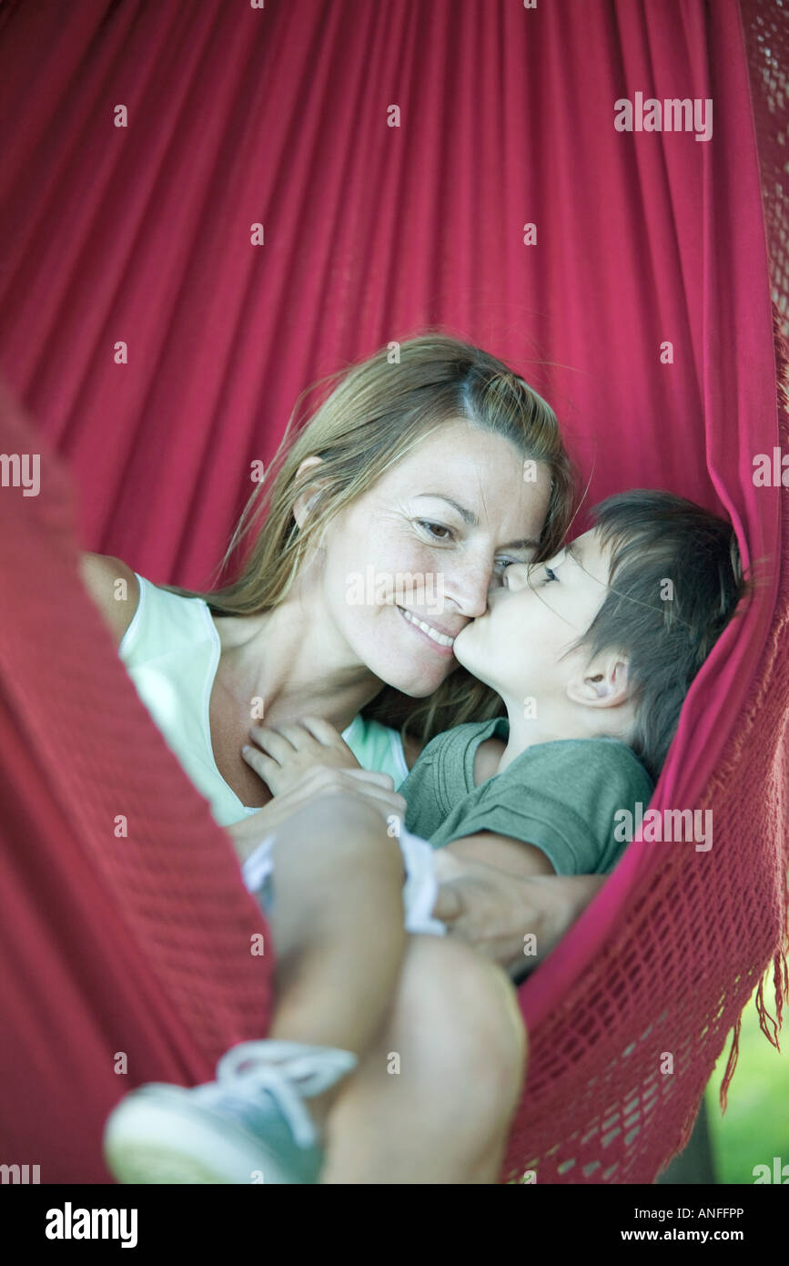 Ragazzo e madre in amaca, ragazzo baciare volto di donna Foto Stock