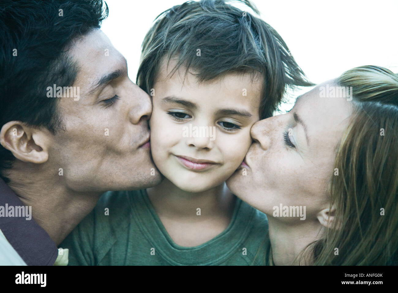 L uomo e la donna baciare figlio sulle guance, close-up Foto Stock