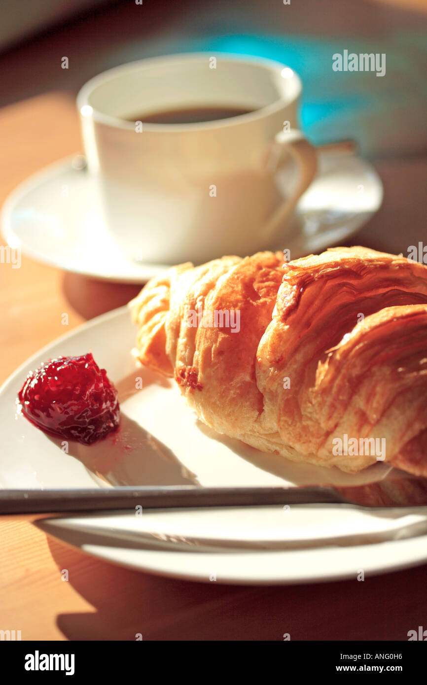 Caffè e Croissant su bianco porcellana Vasellame in presenza di luce solare - verticale Foto Stock