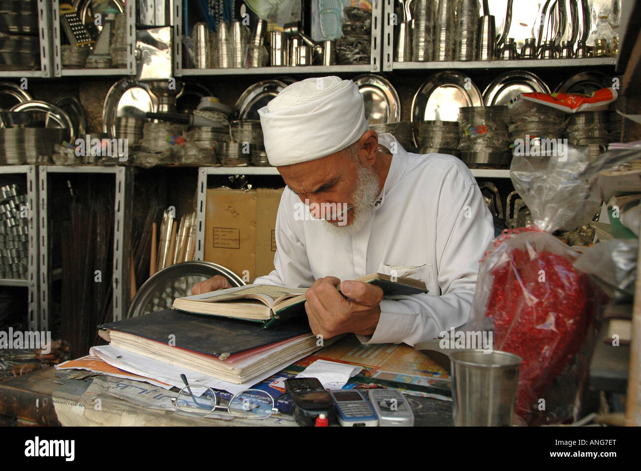 Un anziano uomo egiziano indossando il tradizionale indumento la lettura del Corano il libro sacro al rame-smiths bazaar nella vecchia città del Cairo in Egitto Foto Stock