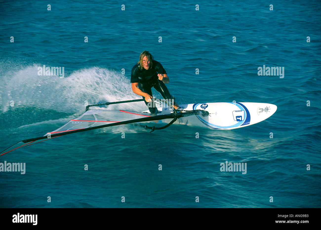 Capelli lunghi windsurfer maschio esegue una sola mano stabilisce gybe accendere il Mar Rosso il Sinai Egitto Foto Stock