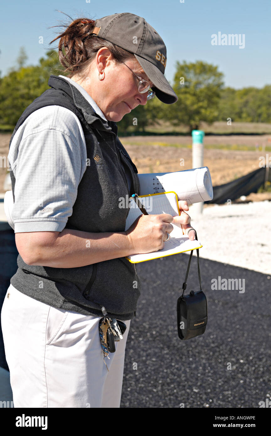 Conserva Deerfield Illinois donna ingegnere rendere note in notebook durante l'installazione di pavimentazione piani laminati sotto braccio Foto Stock