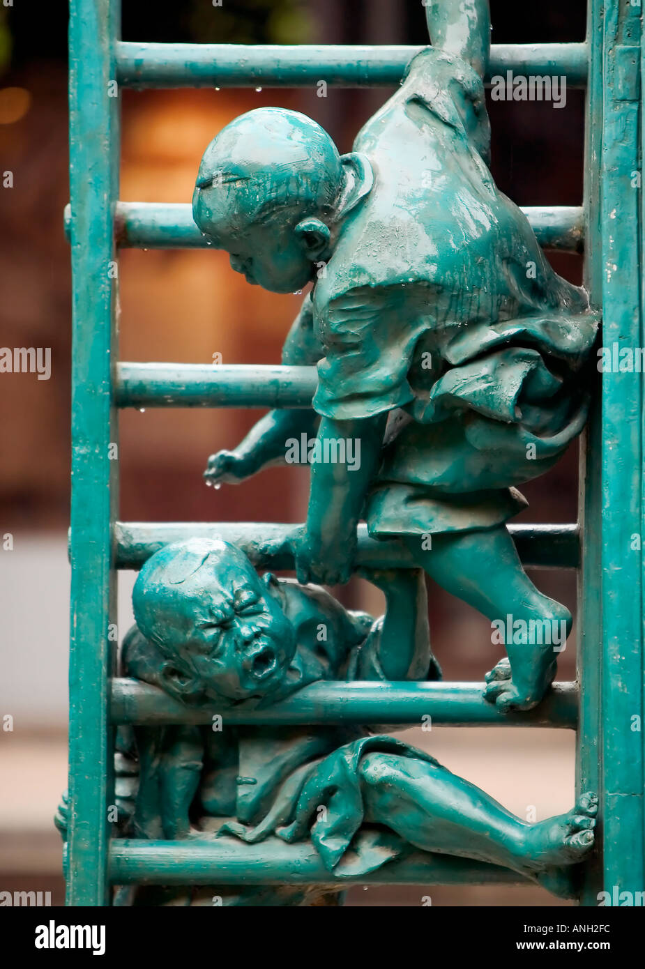 Un metallo verde statua di due bambini che giocano su una scala, uno con la loro testa bloccata tra i pioli e gli altri cercando di aiutare, Guangzhou, Cina Foto Stock