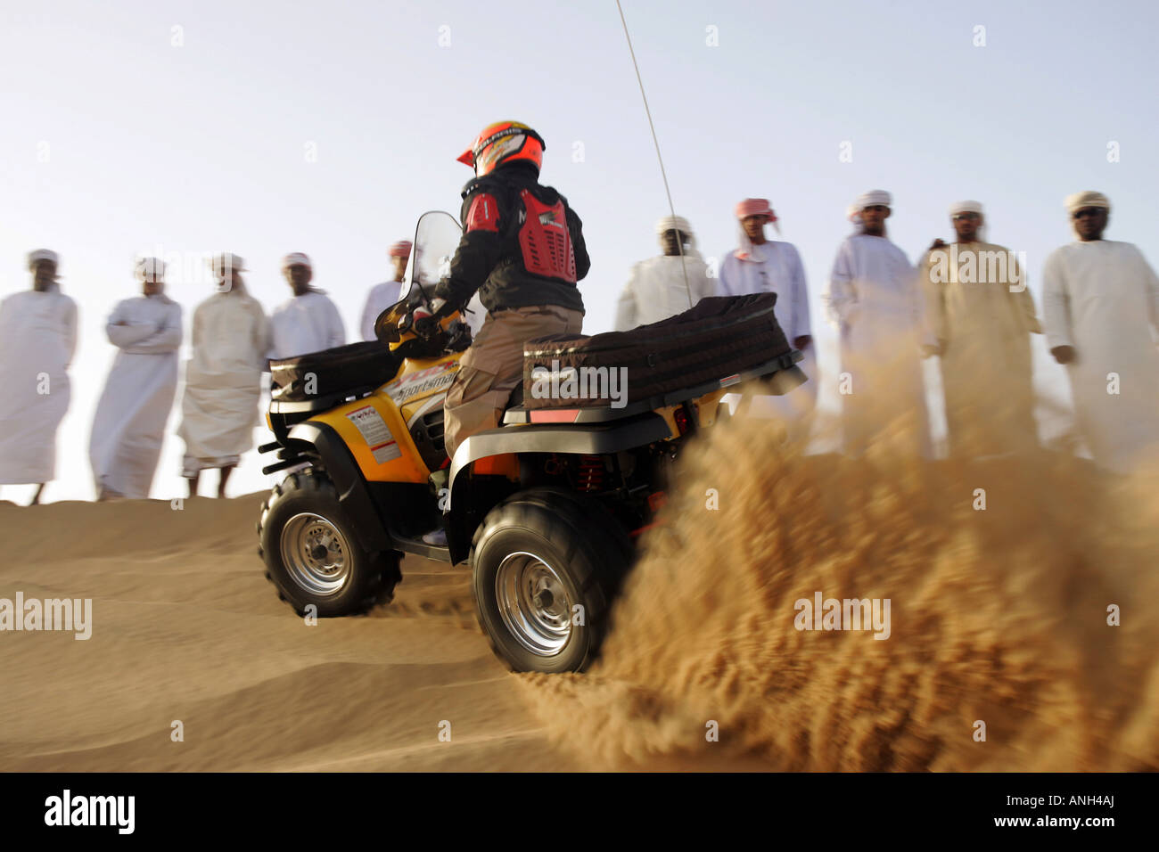 Gruppo di uomini arabi nel deserto guardando un quad rider Foto Stock