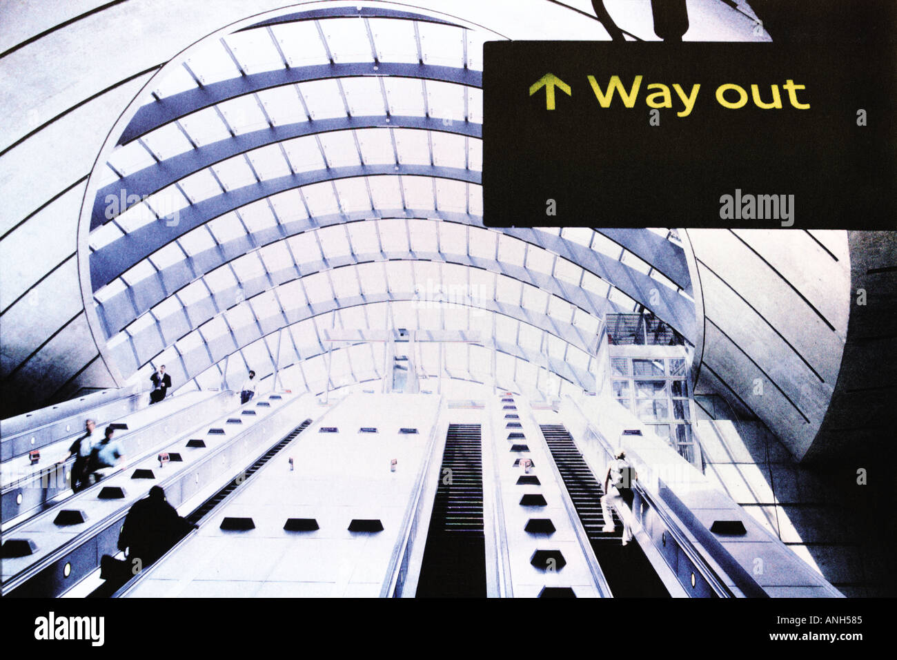 Uscita segno alla stazione della metropolitana Canary Wharf a Londra con scale mobili e gente Foto Stock