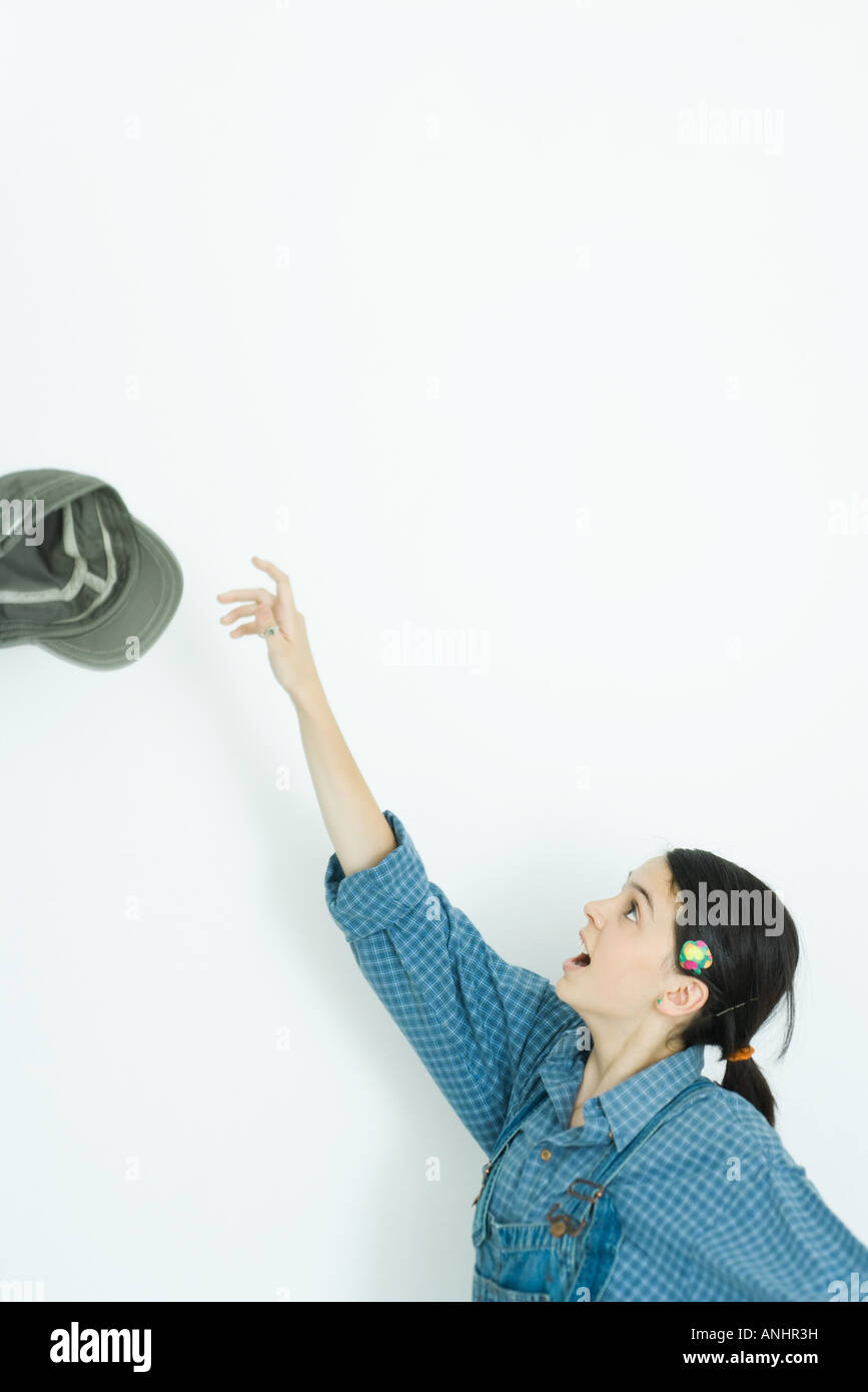 Ragazza adolescente gettando il cappello in aria, vista laterale Foto Stock