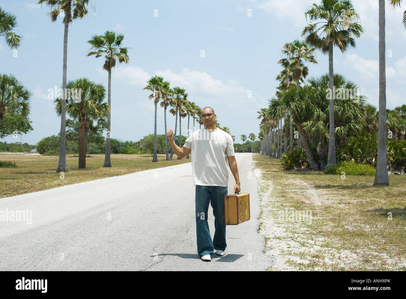 L'uomo autostop accanto alla strada, valigetta Foto Stock