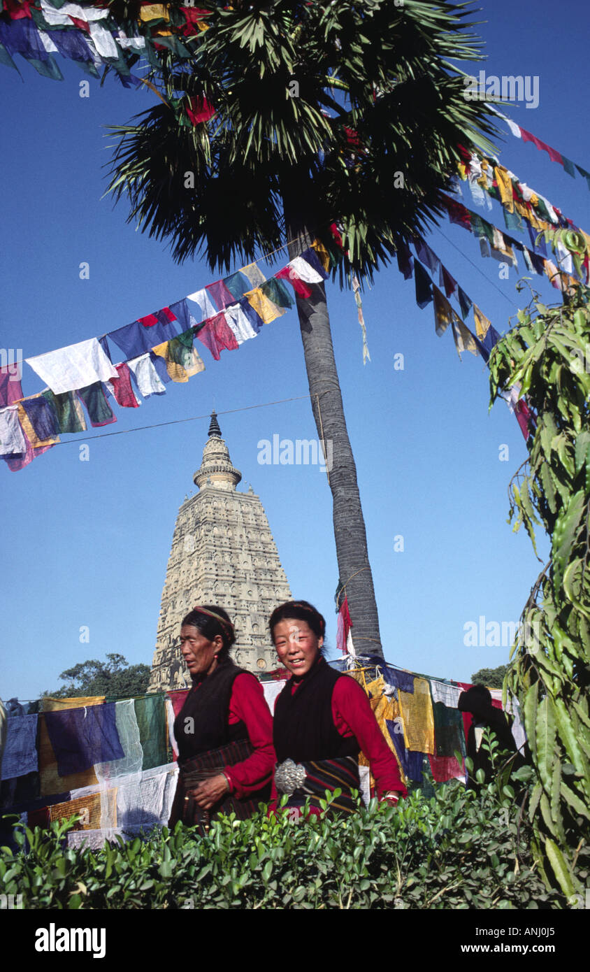 Pellegrini buddisti tibetani in abito tradizionale che circumambulano il tempio Mahabodhi disseminato di bandiere di preghiera, per guadagnare merito, Bodh Gaya, Bihar, India Foto Stock