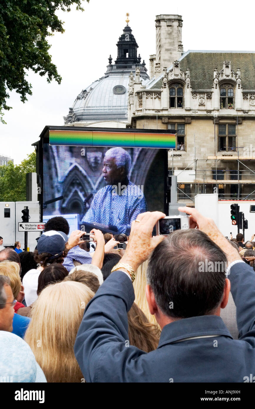 La folla guarda Nelson Mandela su un grande schermo all'inaugurazione di una sua statua in piazza del Parlamento, Londra, 2007. Foto Stock