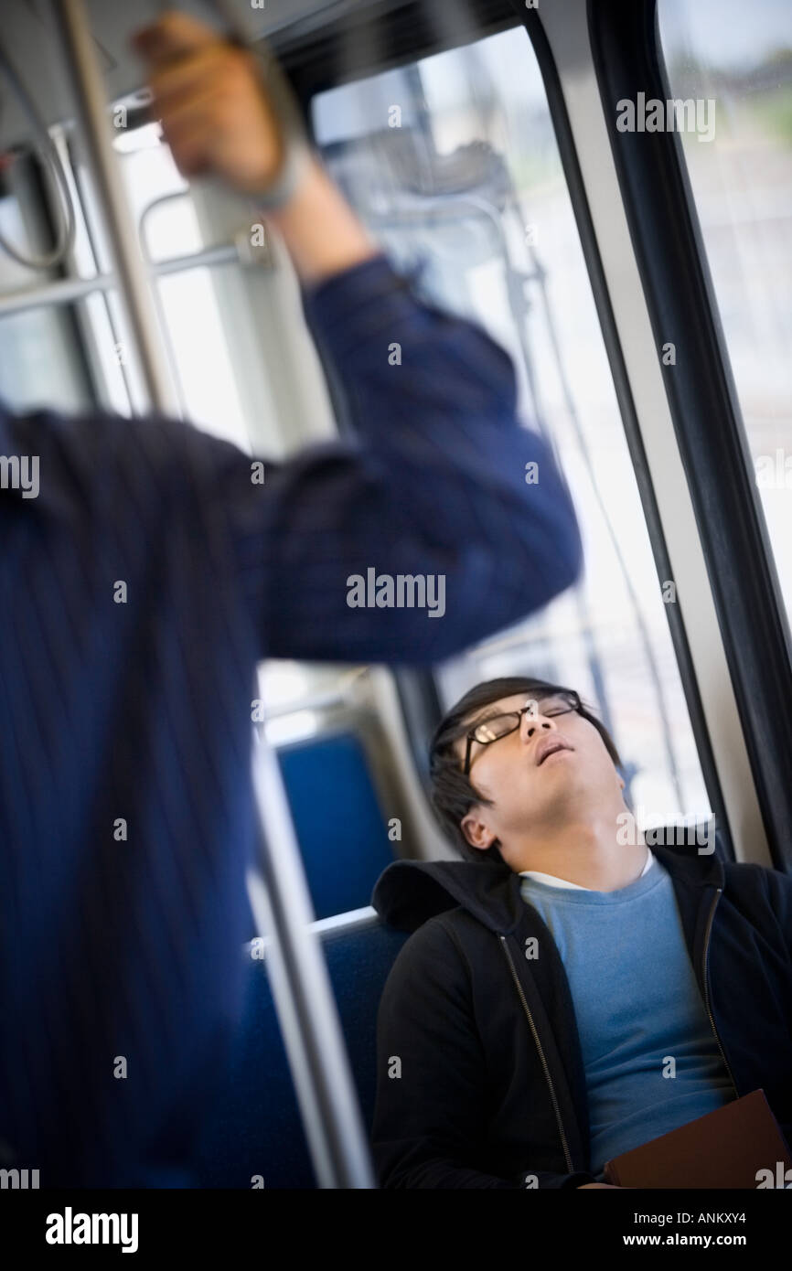 Giovane uomo dorme in un treno della metropolitana Foto Stock