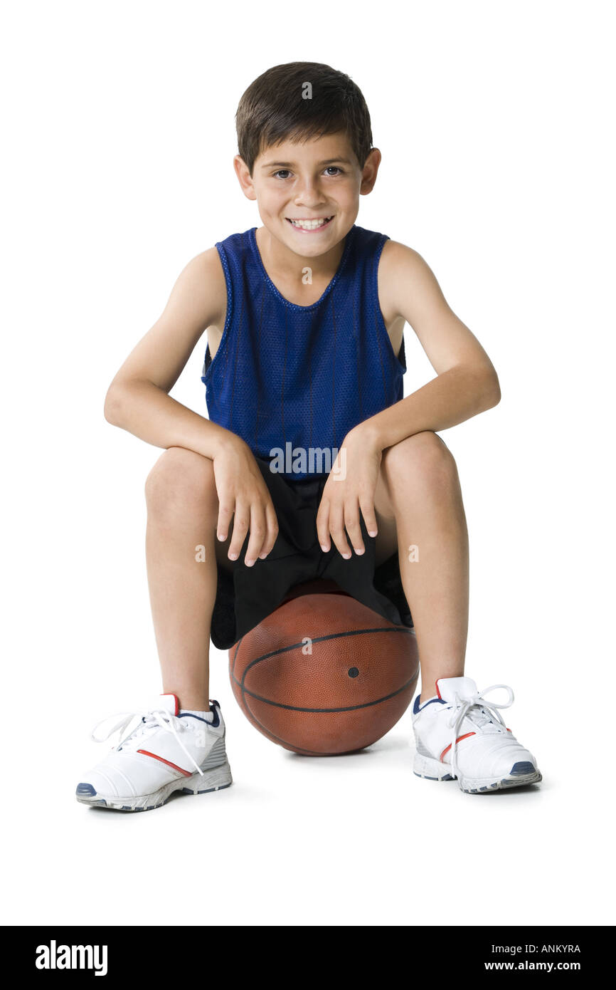Ritratto di un ragazzo seduto su un pallone da basket Foto stock