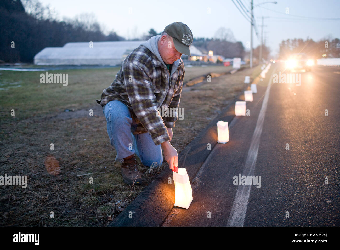 Un uomo luminare luci di candele lungo una strada nel Cheshire Connecticut per commemorare la morte di tre vittime di omicidio. Foto Stock