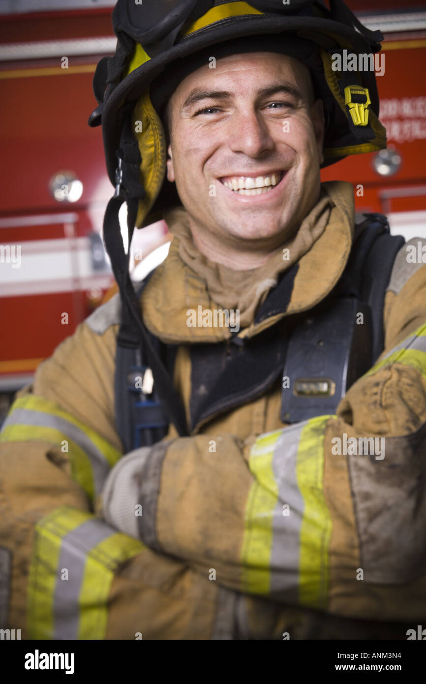 Close up di un vigile del fuoco sorridente con le braccia incrociate Foto Stock