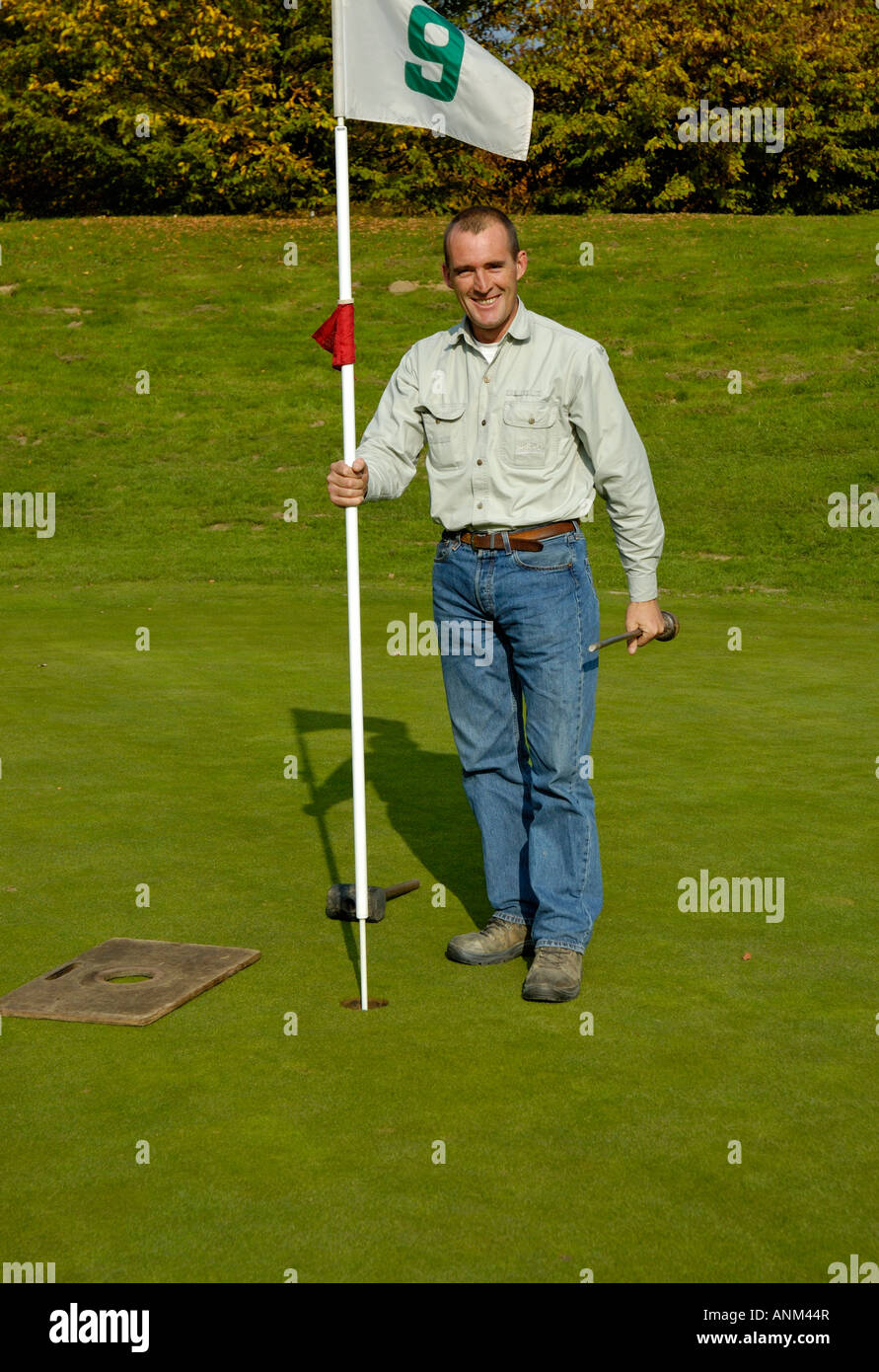 Capo Verde-keeper mettendo il flag nel nuovo foro sul campo da golf. Foto Stock