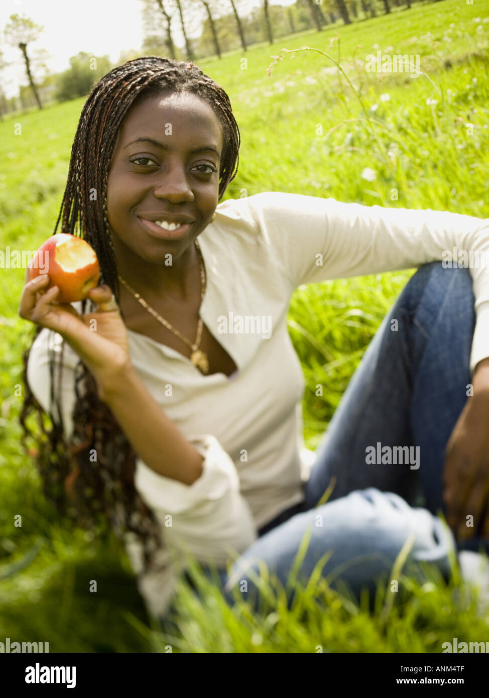 Ritratto di una ragazza seduta in un campo e tenendo un Apple Foto Stock