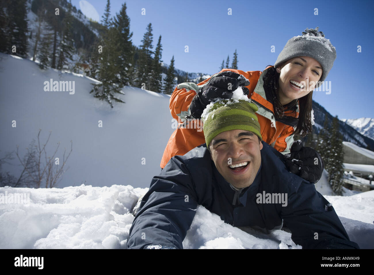 Ritratto di donna seduta su un uomo s indietro nella neve Foto Stock
