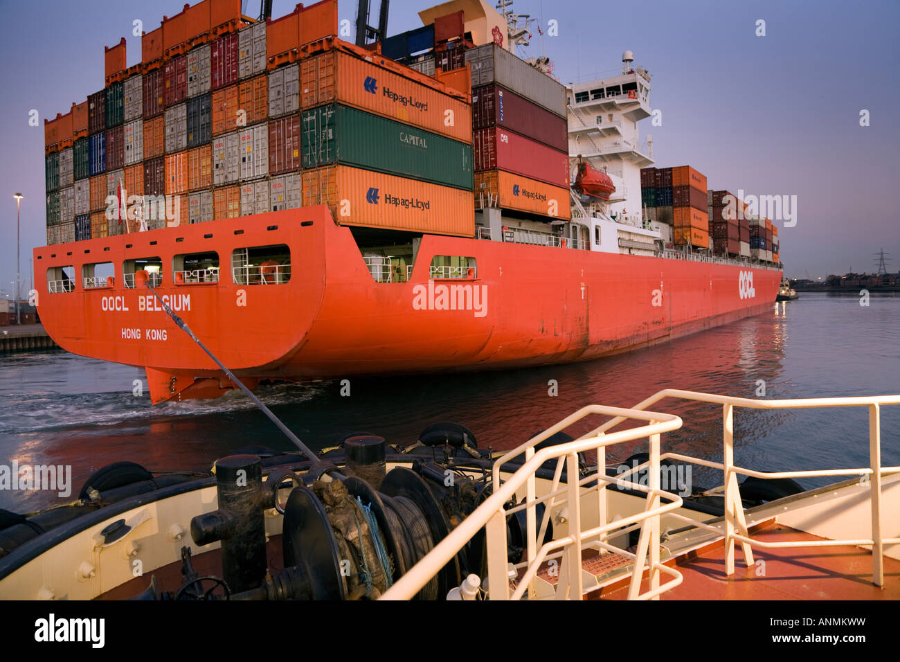 OOCL Belgio nave container essendo tirato dal rimorchiatore lasciando Southampton Docks Foto Stock