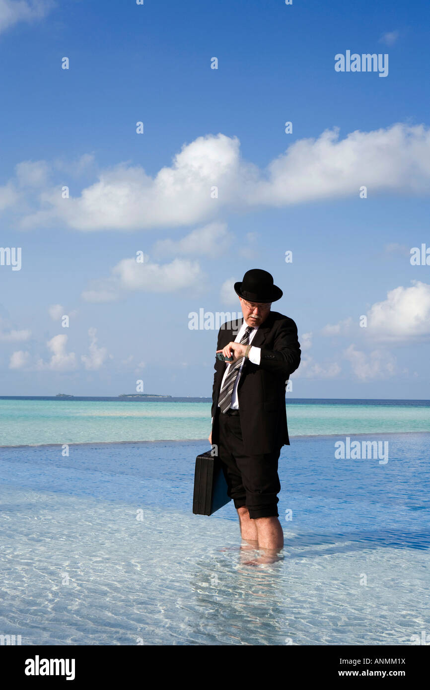 Maldive surriscaldamento imprenditore occidentale vestita in Bowler cappello e business suit controllo orologio Rolex si fermò in piscina Foto Stock