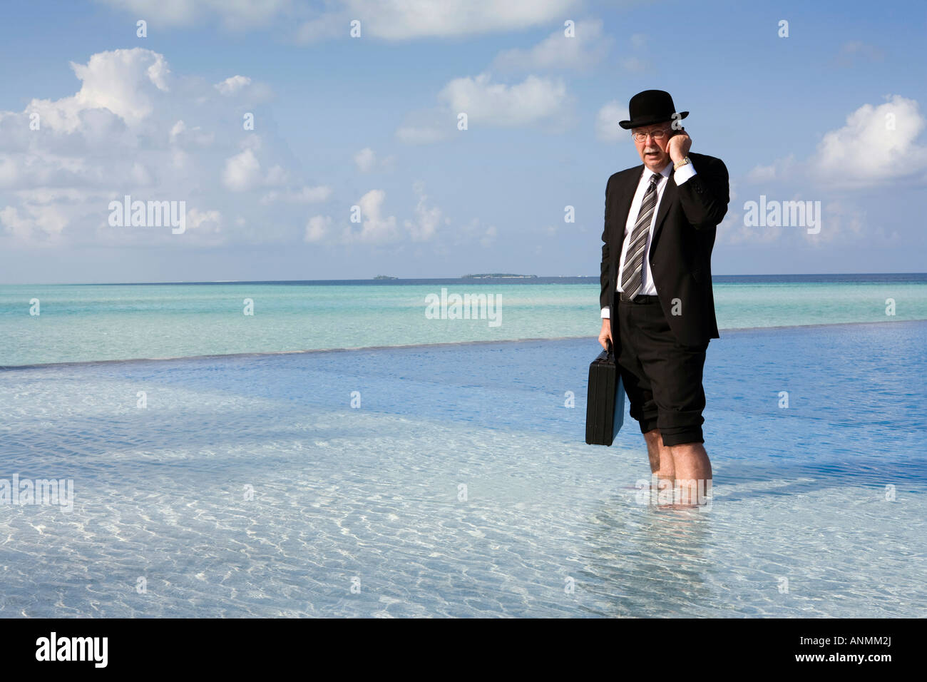 Maldive surriscaldamento imprenditore occidentale vestita in Bowler cappello e business suit sul telefono cellulare si fermò in piscina Foto Stock