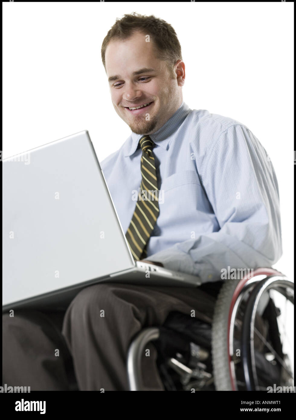 Close up di un giovane uomo seduto in una sedia a rotelle usando un computer portatile Foto Stock