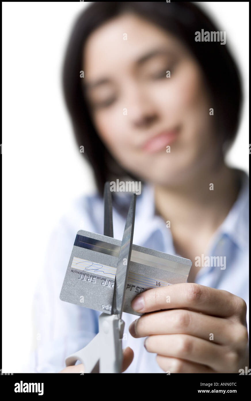 In prossimità di una giovane donna di taglio di una carta di credito con un paio di forbici Foto Stock