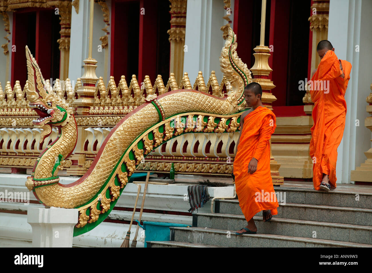 Due monaci in abiti dello zafferano lasciare Nong Wan tempio Muang dettaglio del Golden Dragon che le guardie passi al tempio di Khon Kaen Foto Stock
