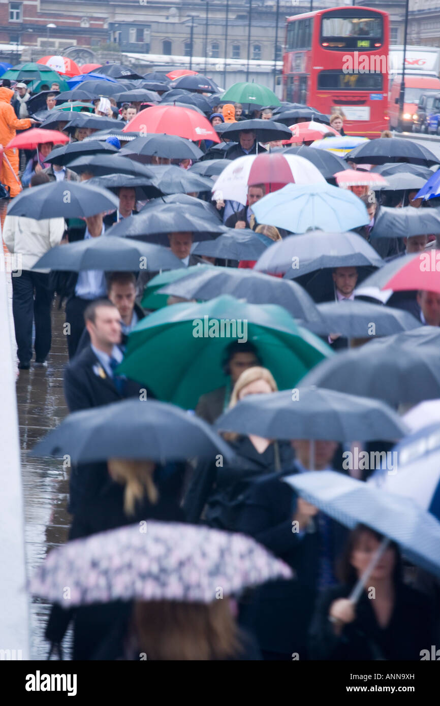 Regno Unito Londra Commutors sotto la pioggia sul Ponte di Londra Foto Stock