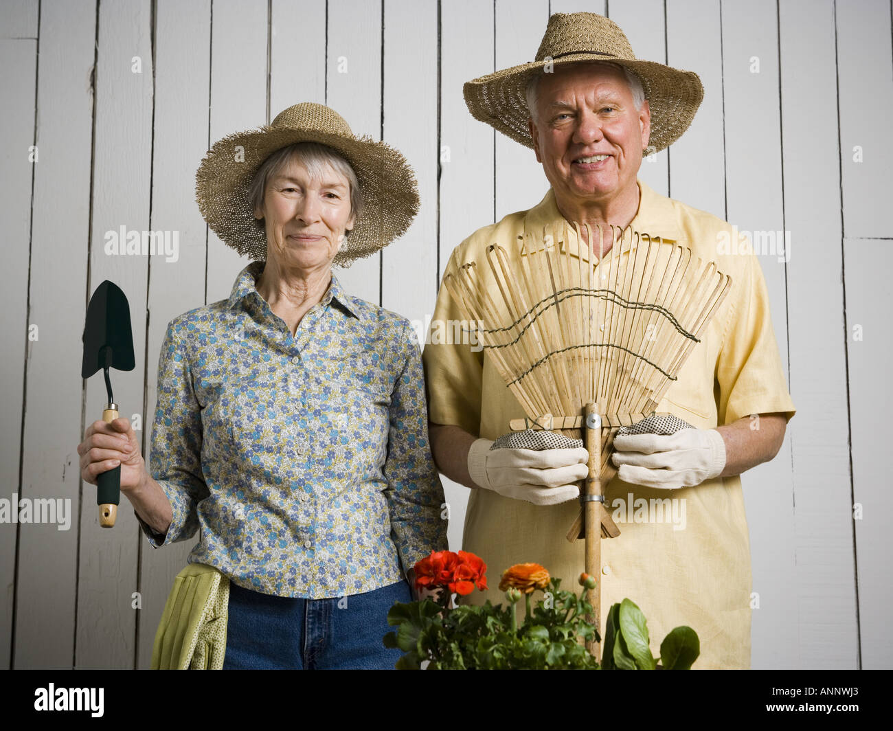 Ritratto di una coppia di anziani in piedi con gli utensili da giardinaggio Foto Stock
