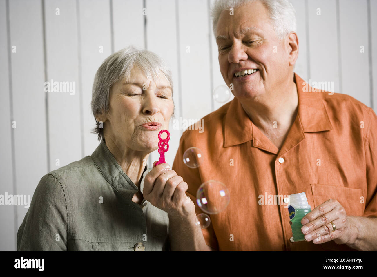In prossimità di una coppia di anziani a soffiare bolle con una bacchetta di bolle Foto Stock