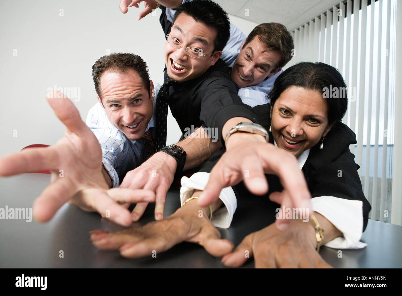 Ritratto di un gruppo di dirigenti aziendali raggiungendo verso una telecamera Foto Stock