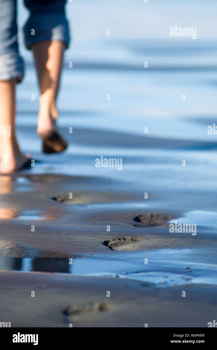 Orme nella sabbia di donna single camminando lungo la spiaggia vuota a Cape Foulwind, Nuova Zelanda Foto Stock