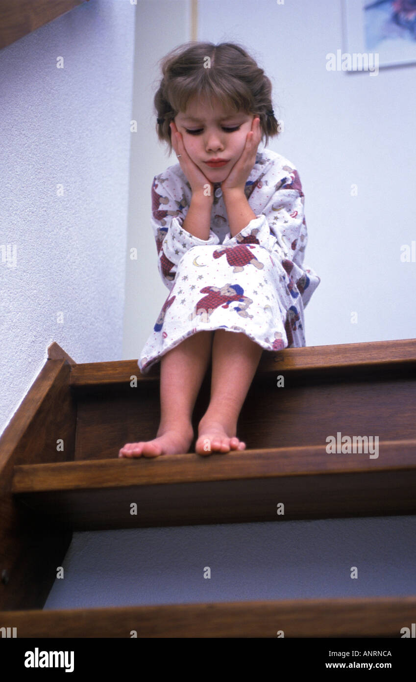 Poco ragazza seduta su una scala in un umore triste Foto Stock