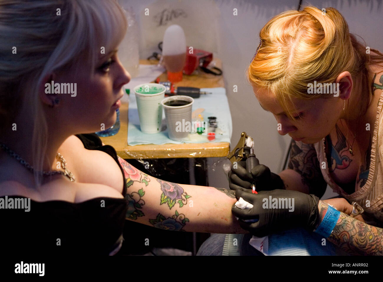 Signora giovane avente il suo male tatuato al primo london international tattoo convention Foto Stock