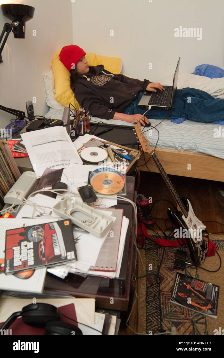 Un ragazzo adolescente utilizzando un lap top nella sua sudicia camera da letto Foto Stock