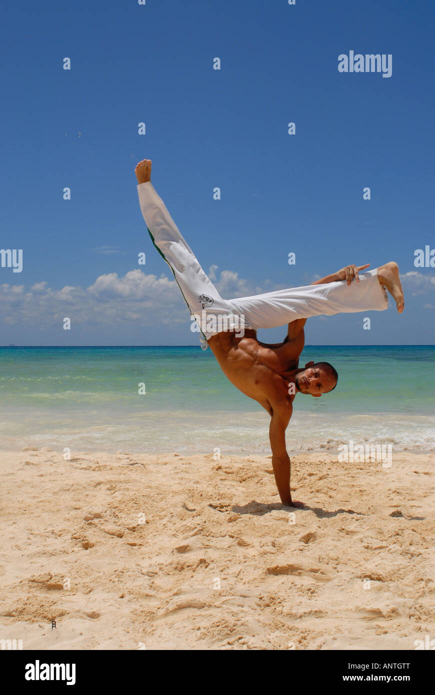 Un uomo praticando Capoeira sulla spiaggia Foto Stock