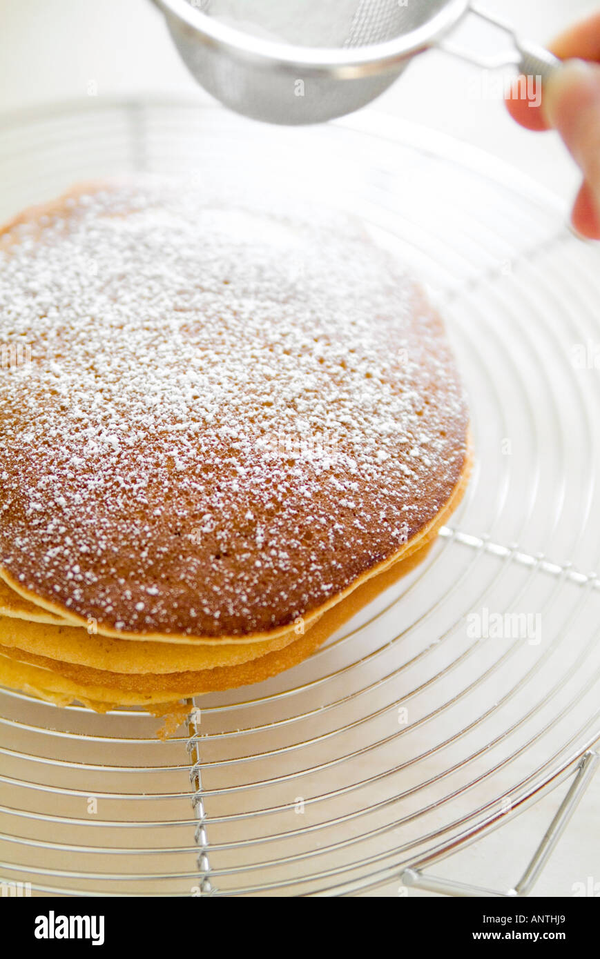 Setacciatura dello zucchero sul pancake Foto Stock