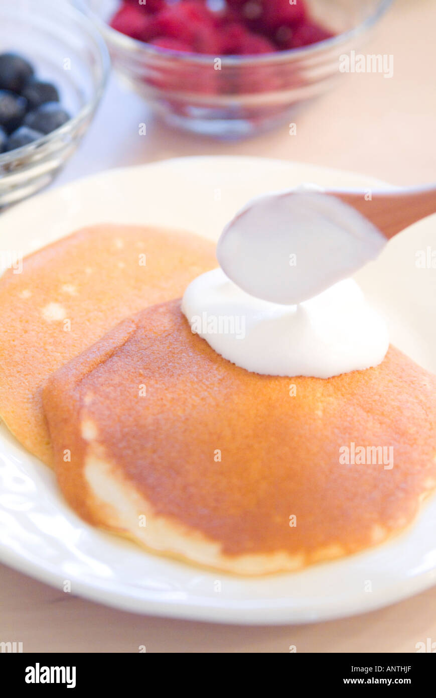 Mettere la panna montata su pancake Foto Stock